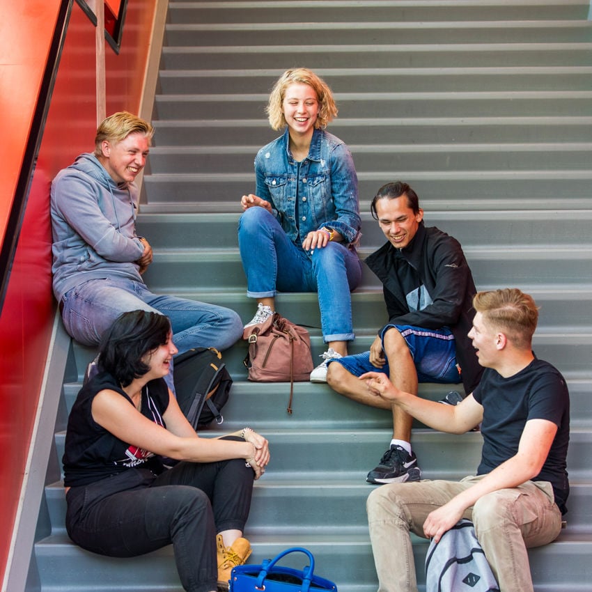 Docent leidt groep lachende studenten in klaslokaal