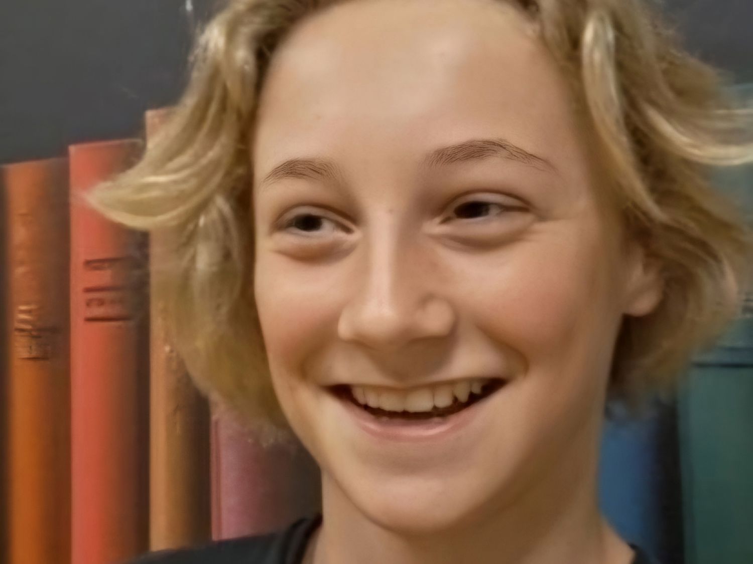 Leerling lachend voor een boekenkast