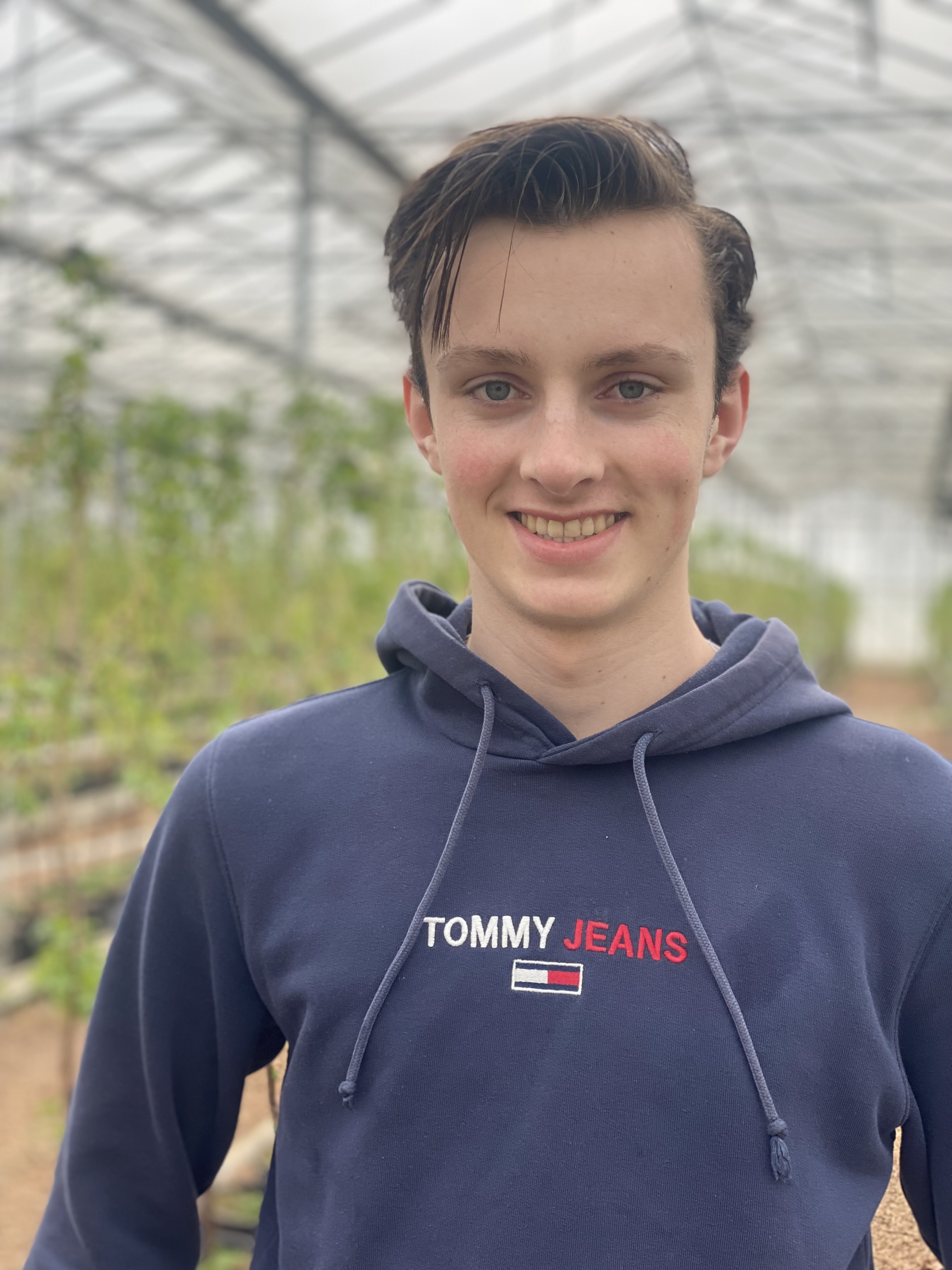 Jongen in close-up met op de achtergrond een fruitteeltkas